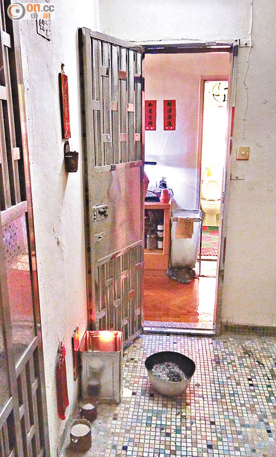 青年的家人在住所門外燃點白蠟燭。